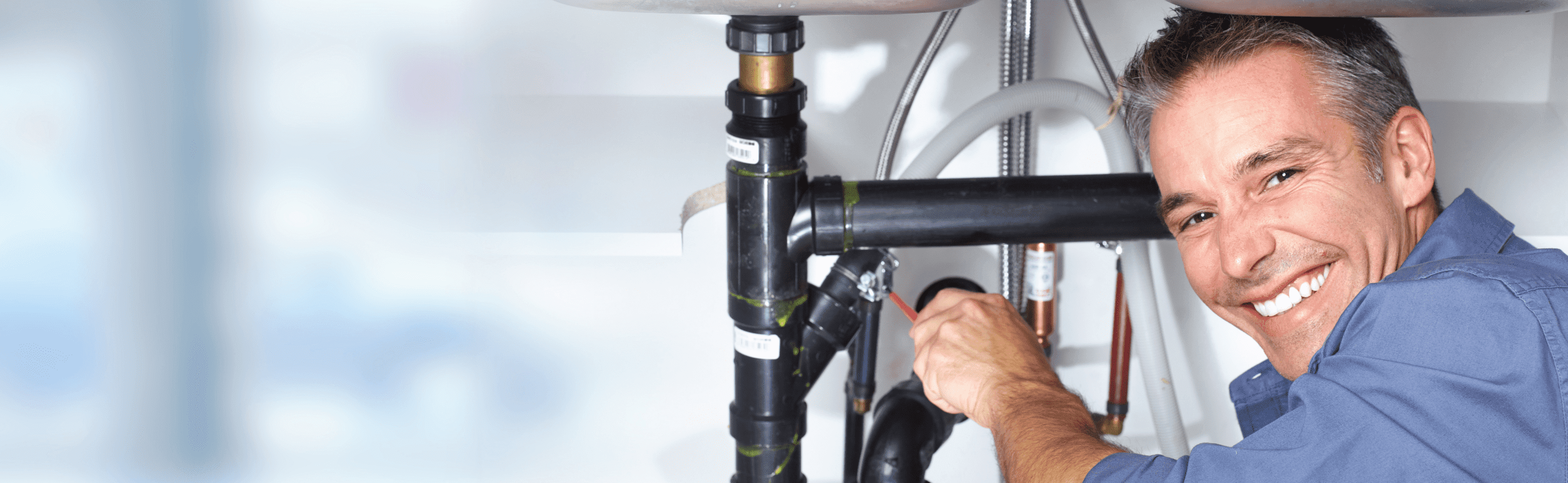 Plumber repairing pipes under sink